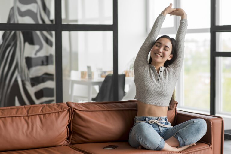 Woman enjoying a peaceful morning stretch on a leather couch inside a bright living room of luxury 4 BHK villa in Mandi Gwal Pahari by CS Realty.